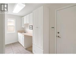 Walk-in laundry room with a sink and ample storage options - 