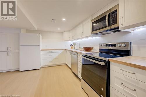 Kitchen with decorative backsplash, stainless steel appliances, light hardwood / wood-style flooring, white cabinets, and butcher block counters - 209 Cornwall Street, Waterloo, ON - Indoor Photo Showing Kitchen