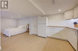 Bedroom with white refrigerator and light hardwood / wood-style floors - 