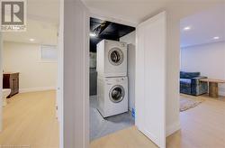 Laundry area with light hardwood / wood-style floors and stacked washer and dryer - 