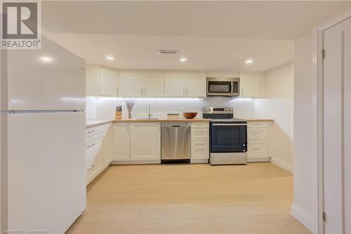 Kitchen featuring white cabinetry, sink, stainless steel appliances, tasteful backsplash, and light hardwood / wood-style floors - 209 Cornwall Street, Waterloo, ON - Indoor Photo Showing Kitchen