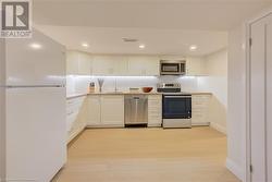 Kitchen featuring white cabinetry, sink, stainless steel appliances, tasteful backsplash, and light hardwood / wood-style floors - 