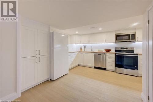 Kitchen featuring backsplash, white cabinets, sink, light wood-type flooring, and stainless steel appliances - 209 Cornwall Street, Waterloo, ON - Indoor Photo Showing Kitchen