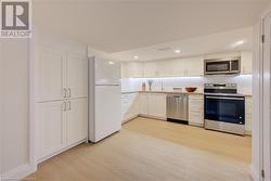 Kitchen featuring backsplash, white cabinets, sink, light wood-type flooring, and stainless steel appliances - 