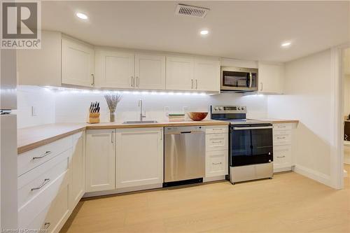 Kitchen featuring white cabinetry, sink, light hardwood / wood-style floors, and appliances with stainless steel finishes - 209 Cornwall Street, Waterloo, ON - Indoor Photo Showing Kitchen