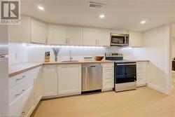 Kitchen featuring white cabinetry, sink, light hardwood / wood-style floors, and appliances with stainless steel finishes - 