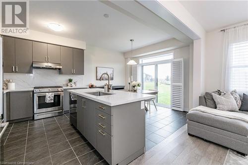 Kitchen with appliances with stainless steel finishes, a kitchen island with sink, sink, pendant lighting, and gray cabinets - 116 Whithorn Crescent, Caledonia, ON - Indoor Photo Showing Kitchen