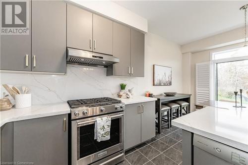 Kitchen with gray cabinetry, pendant lighting, high end range, backsplash, and exhaust hood - 116 Whithorn Crescent, Caledonia, ON - Indoor Photo Showing Kitchen