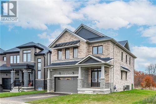 View of front of house with a front lawn, a garage, and central AC unit - 116 Whithorn Crescent, Caledonia, ON - Outdoor With Facade