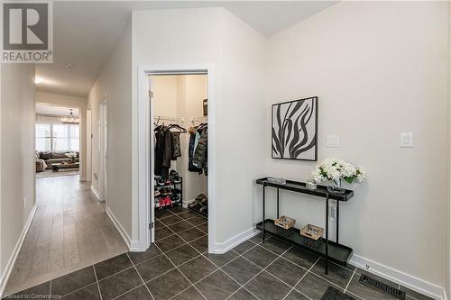 Hallway with dark tile patterned flooring and a notable chandelier - 116 Whithorn Crescent, Caledonia, ON - Indoor Photo Showing Other Room