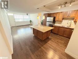 Kitchen featuring sink, hanging light fixtures, ceiling fan, stainless steel fridge, and baseboard heating - 