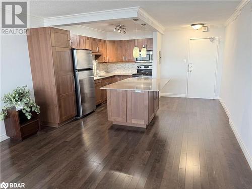 Kitchen with decorative backsplash, appliances with stainless steel finishes, decorative light fixtures, a center island, and dark hardwood / wood-style floors - 2263 Marine Drive Unit# 607, Oakville, ON 