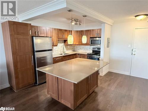 Kitchen with decorative backsplash, stainless steel appliances, sink, pendant lighting, and a kitchen island - 2263 Marine Drive Unit# 607, Oakville, ON 