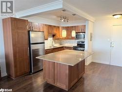 Kitchen with a center island, dark wood-type flooring, hanging light fixtures, decorative backsplash, and stainless steel appliances - 