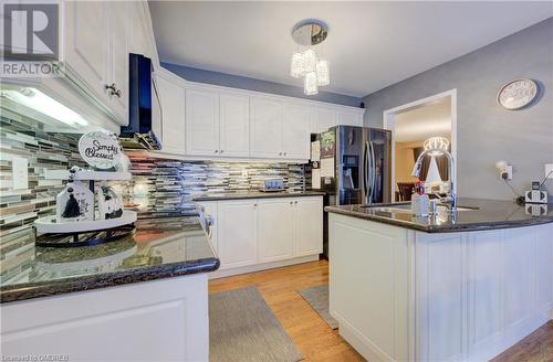 Kitchen with white cabinets, sink, light hardwood / wood-style flooring, and backsplash - 32 Triller Avenue, Cambridge, ON - Indoor Photo Showing Kitchen