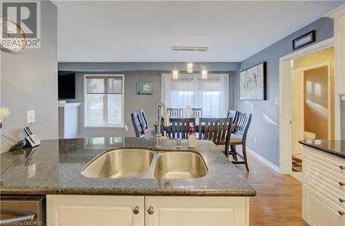 Kitchen featuring dark stone counters, white cabinets, sink, and light hardwood / wood-style flooring - 32 Triller Avenue, Cambridge, ON - Indoor Photo Showing Kitchen With Double Sink