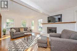 Living room with beamed ceiling, a brick fireplace, and light hardwood / wood-style flooring - 