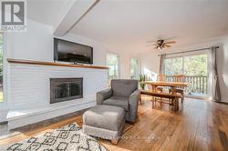 Living room featuring ceiling fan, light hardwood / wood-style flooring, and a brick fireplace - 