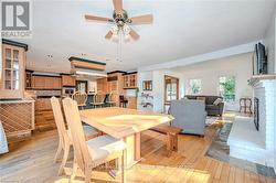 Dining room featuring a fireplace, a textured ceiling, light wood-type flooring, and ceiling fan - 