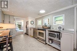 Kitchen with sink, plenty of natural light, a textured ceiling, and appliances with stainless steel finishes - 