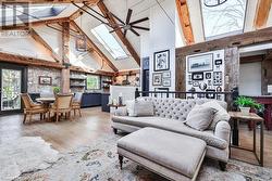 Living room featuring a skylight, light hardwood / wood-style flooring, high vaulted ceiling, and beamed ceiling - 