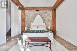 Bedroom with beamed ceiling and light wood-type flooring - 