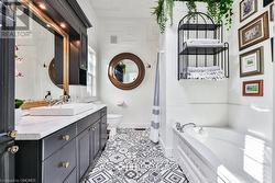 Bathroom with tiled bath, tile patterned flooring, vanity, and toilet - 