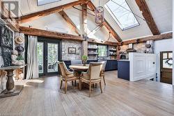 Dining area with beamed ceiling, high vaulted ceiling, a skylight, and light hardwood / wood-style flooring - 