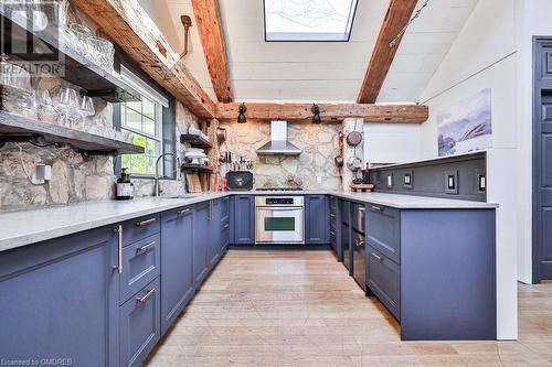 Kitchen featuring appliances with stainless steel finishes, wall chimney exhaust hood, sink, blue cabinetry, and vaulted ceiling with beams - 1486 Kenmuir Avenue, Mississauga, ON - Indoor Photo Showing Kitchen