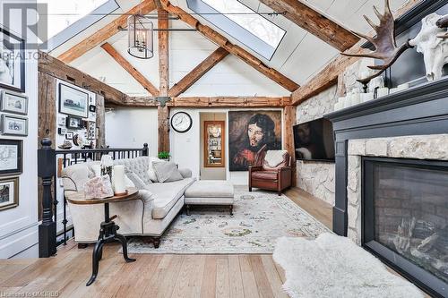 Living room featuring vaulted ceiling with beams, a stone fireplace, light wood-type flooring, and a chandelier - 1486 Kenmuir Avenue, Mississauga, ON - Indoor Photo Showing Living Room With Fireplace