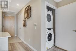 Washroom with light hardwood / wood-style flooring and stacked washer and clothes dryer - 