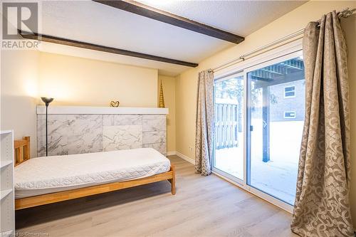 Bedroom with access to exterior, hardwood / wood-style floors, a textured ceiling, and beam ceiling - 212 Westcourt Place, Waterloo, ON - Indoor Photo Showing Bedroom