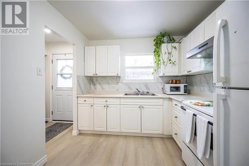 Kitchen with white cabinetry, sink, and white appliances - 212 Westcourt Place, Waterloo, ON - Indoor Photo Showing Kitchen With Double Sink