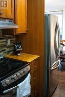 Kitchen featuring backsplash, hardwood / wood-style flooring, stainless steel fridge, range hood, and white electric range oven - 