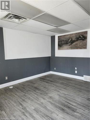 Empty room featuring a paneled ceiling and dark hardwood / wood-style flooring - 26 Elmwood Avenue, Cambridge, ON 