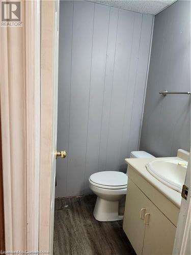 Bathroom featuring toilet, hardwood / wood-style flooring, wood walls, and vanity - 26 Elmwood Avenue, Cambridge, ON 