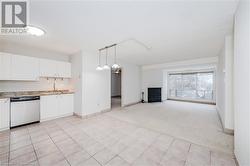 Kitchen with hanging light fixtures, light colored carpet, dishwasher, and white cabinets - 