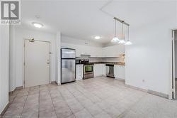 Kitchen with light tile patterned floors, appliances with stainless steel finishes, pendant lighting, and white cabinetry - 