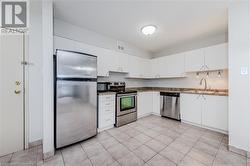 Kitchen featuring appliances with stainless steel finishes, sink, white cabinetry, and dark stone counters - 