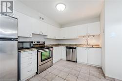 Kitchen featuring sink, white cabinetry, light tile patterned floors, and stainless steel appliances - 