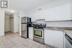 Kitchen with light tile patterned floors, appliances with stainless steel finishes, and white cabinets - 