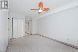 Unfurnished bedroom with ceiling fan, ensuite bathroom, a closet, and light carpet - 