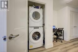 Clothes washing area with stacked washer and dryer and light wood-type flooring - 