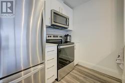 Kitchen featuring light wood-type flooring, white cabinets, decorative backsplash, and stainless steel appliances - 