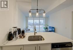 Kitchen featuring white cabinetry, sink, dishwasher, and decorative light fixtures - 