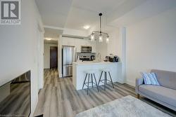 Kitchen with pendant lighting, kitchen peninsula, white cabinetry, appliances with stainless steel finishes, and a kitchen breakfast bar - 