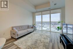 Living room featuring wood-type flooring, floor to ceiling windows, and a raised ceiling - 