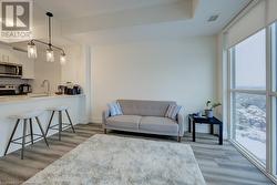 Living room featuring a wealth of natural light, a wall of windows, light hardwood / wood-style flooring, and sink - 