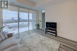 Living room featuring a raised ceiling, floor to ceiling windows, and hardwood / wood-style floors - 