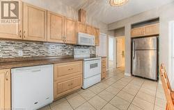 Kitchen with backsplash, white appliances, and light brown cabinets - 